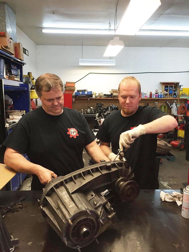 mechanics working with auto repair part